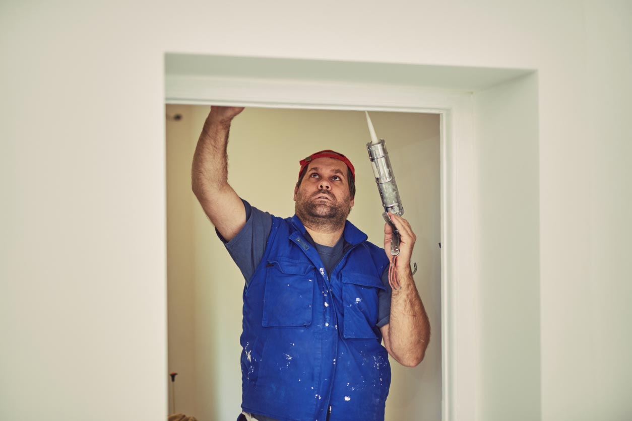 Un homme pose des joints autour de la porte