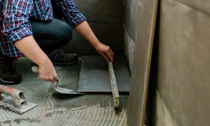 Une femme pose du carrelage