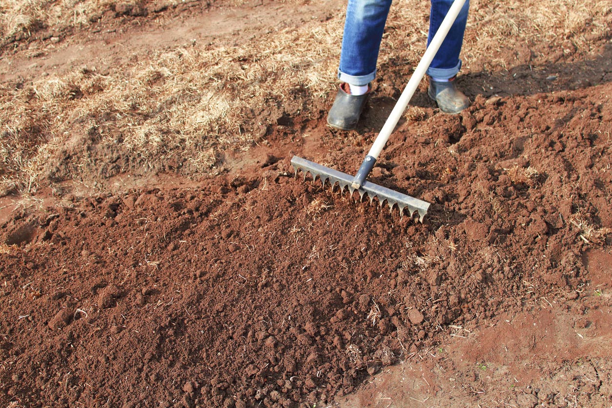 Une femme prépare le sol du potager