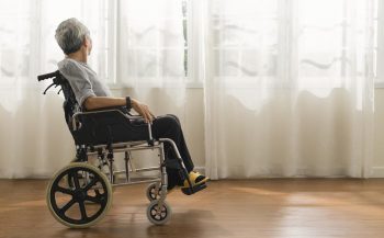 homme en situationde handicap regarde par la fenetre de sa maison