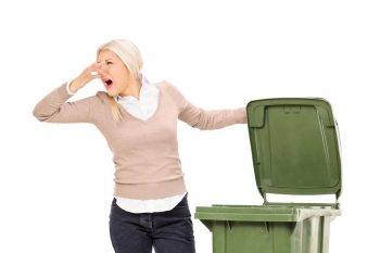 Femme qui ouvre une poubelle qui sent mauvais