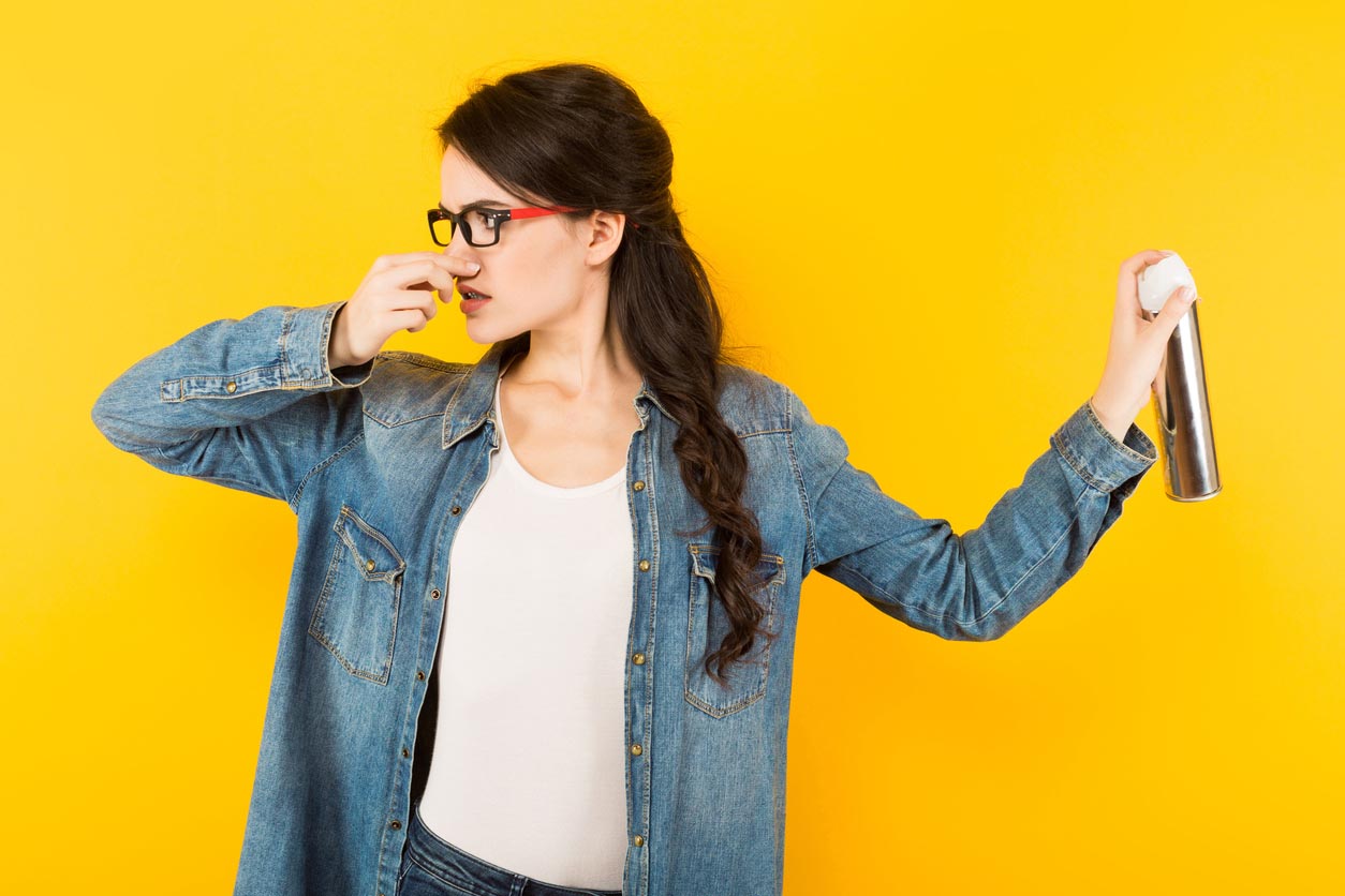 femme se bouche le nez et met du spray