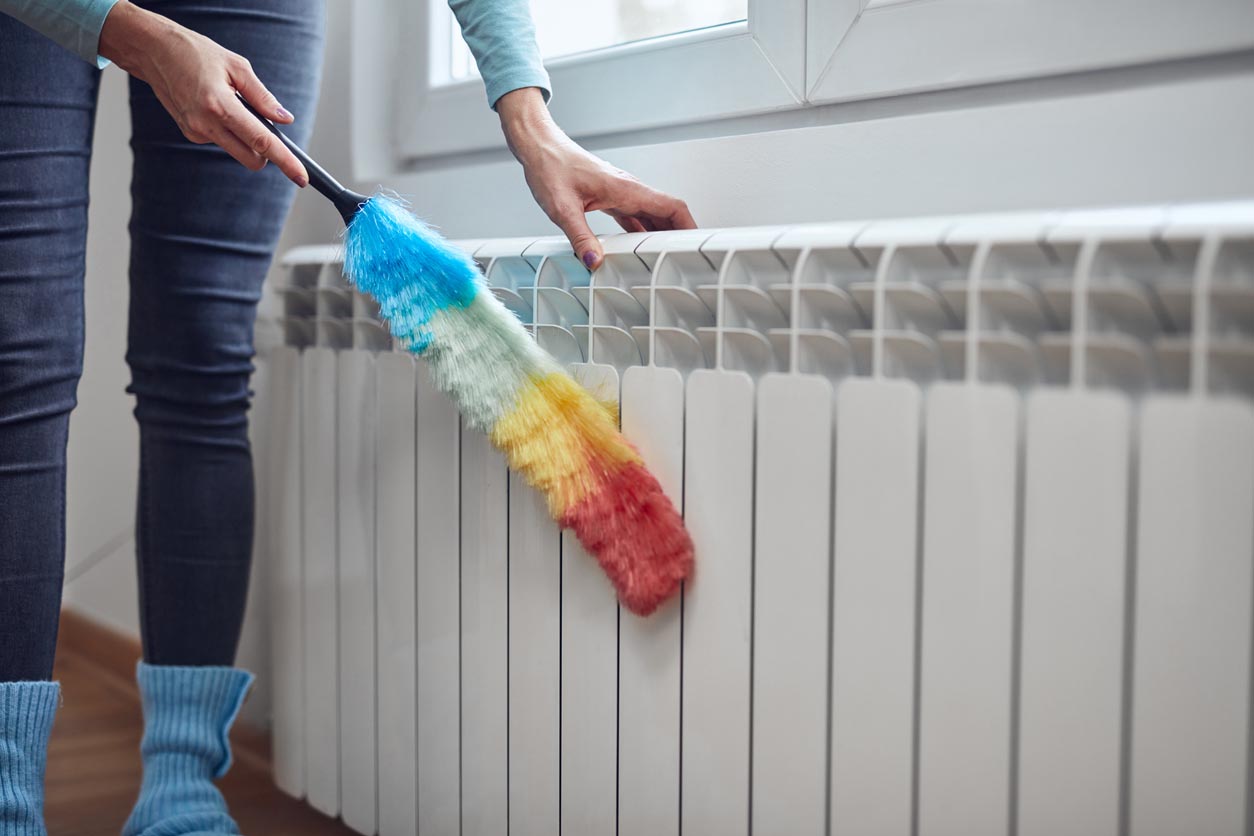 femme nettoyant le radiateur avec un plumo