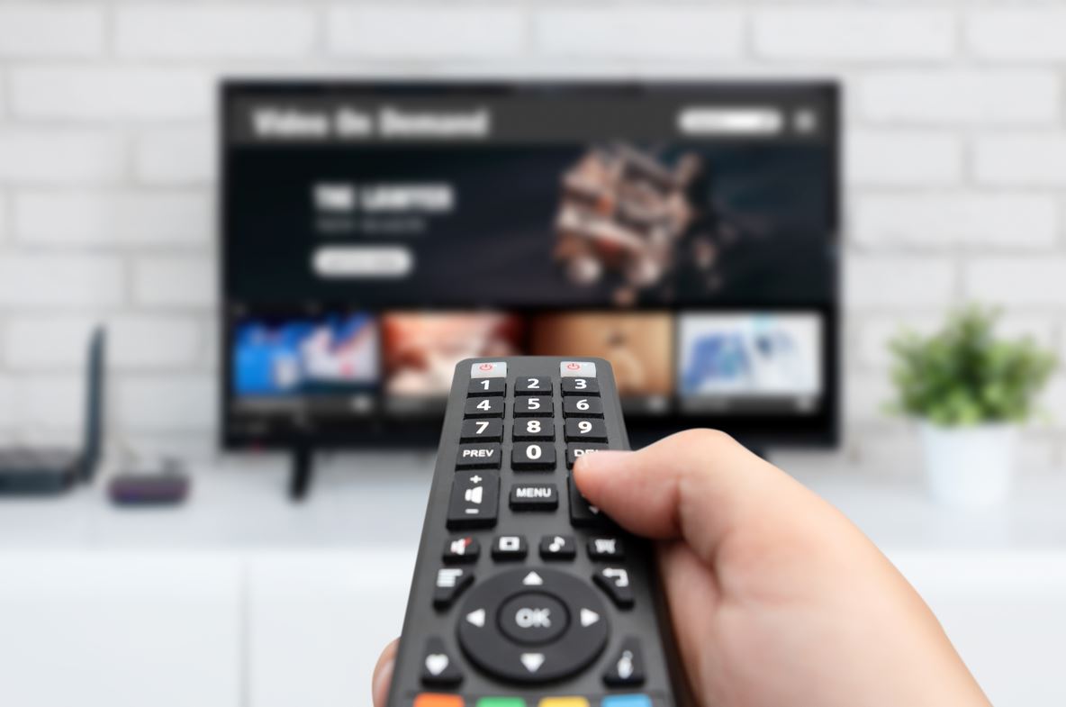 Gros Plan D'une Main Qui Tient Une Télécommande Devant Un Tv