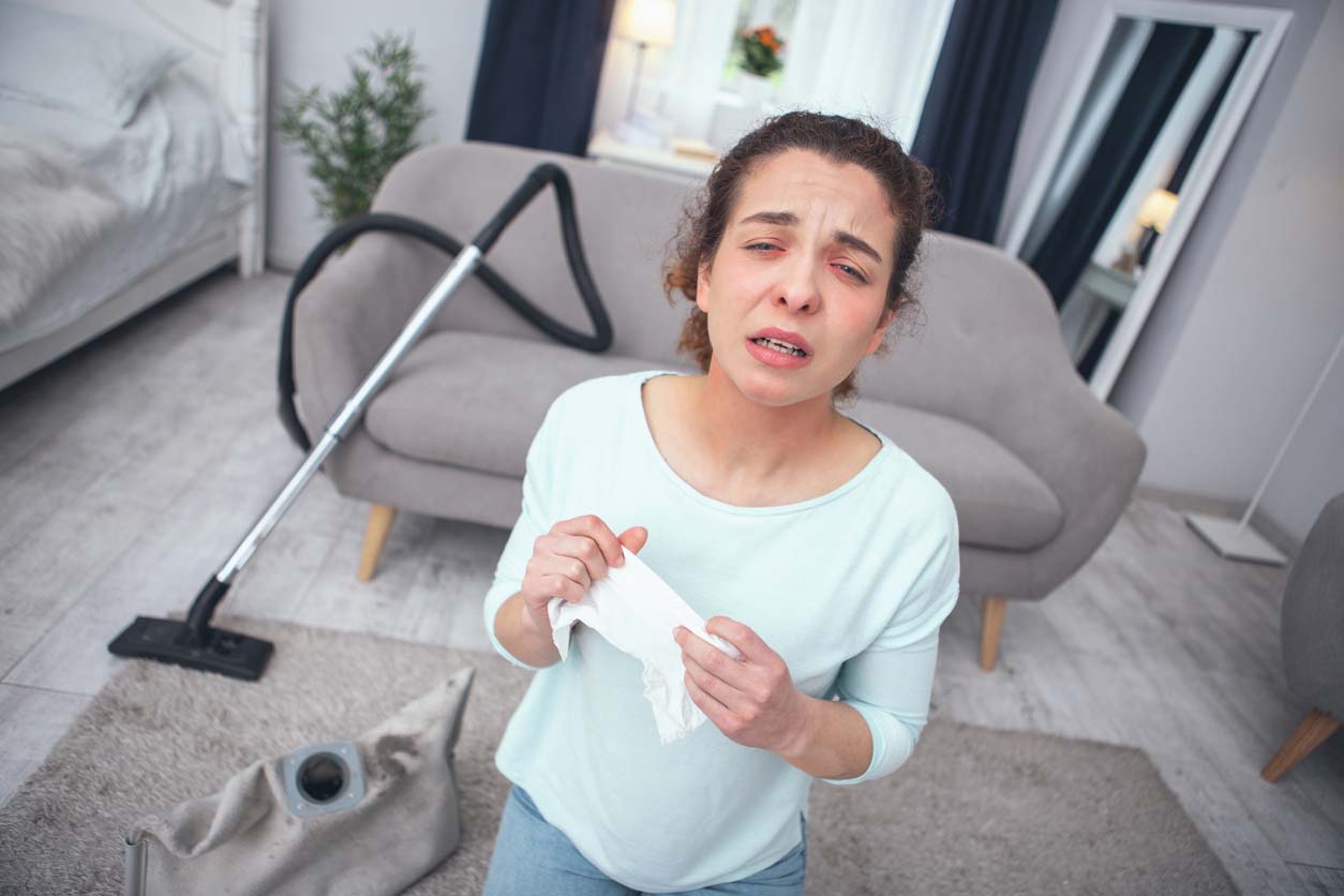 femme ayant des allergies à la poussière en faisant le menage