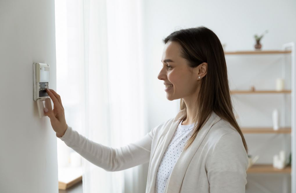 Femme Heureuse D'ajuster La Température De Son Logement équipé D'une Pompe à Chaleur Réversible